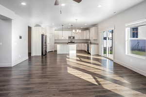 Unfurnished living room featuring recessed lighting, dark wood-style flooring, ceiling fan, a chandelier, and a textured ceiling