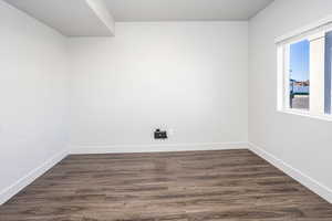 Unfurnished room with dark wood finished floors and baseboards
