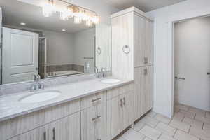 Full bath featuring light tile patterned floors, double vanity, a bath, and a textured ceiling