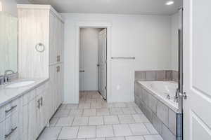 Bathroom with vanity, a garden tub, light tile patterned flooring, and recessed lighting