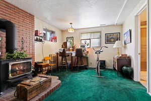 Workout area featuring a wood stove, dark carpet, and a textured ceiling