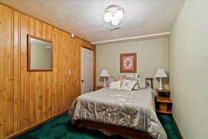 Carpeted bedroom with a textured ceiling and wood walls