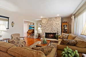 Living room featuring plenty of natural light, a stone fireplace, and laminate floors