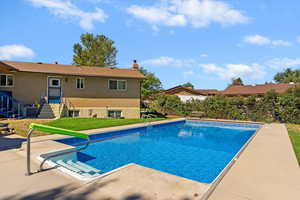 Outdoor pool featuring a yard, a patio area, and entry steps