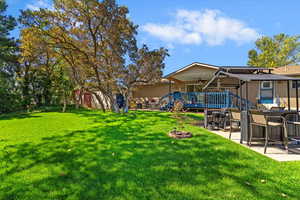 View of grassy yard featuring a patio area and back of house