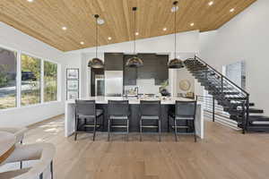 Kitchen with a breakfast bar, pendant lighting, light wood-style flooring, a large island, and wood ceiling