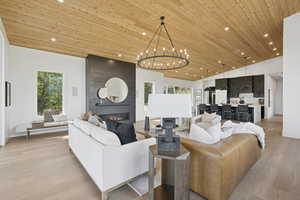 Living room with wooden ceiling, recessed lighting, a large fireplace, light wood finished floors, and a chandelier