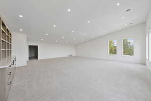 Unfurnished living room featuring recessed lighting, light carpet, and lofted ceiling