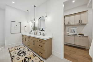 Bathroom with double vanity, recessed lighting, and light wood-style flooring