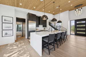 Kitchen featuring pendant lighting, dark cabinets, a breakfast bar, light wood-style floors, and modern cabinets