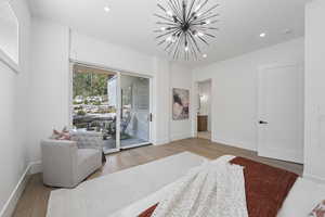 Bedroom with recessed lighting, a chandelier, access to exterior, wood finished floors, and ensuite bath