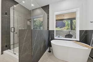 Full bath featuring tile walls, a freestanding tub, a marble finish shower, and recessed lighting
