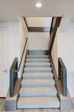 Stairway with wood finished floors and recessed lighting