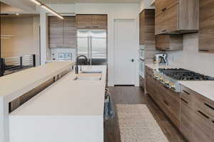 Kitchen with dark wood-style flooring, appliances with stainless steel finishes, light stone countertops, and modern cabinets