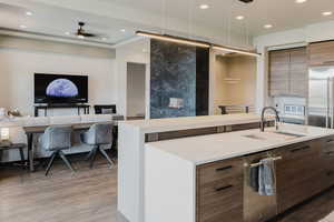 Kitchen with modern cabinets, recessed lighting, open floor plan, light stone counters, and a fireplace