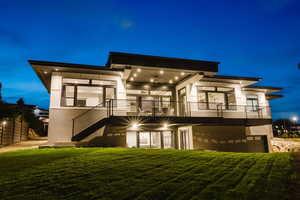 Back of house at night featuring stucco siding, a yard, and a patio