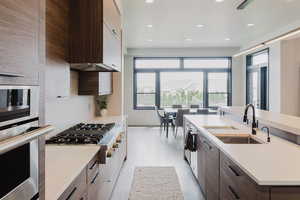 Kitchen featuring dark brown cabinetry, modern cabinets, stainless steel appliances, recessed lighting, and an island with sink