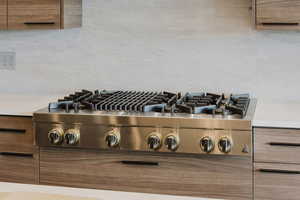 Kitchen view of brown cabinetry, modern cabinets, and stainless steel gas stovetop