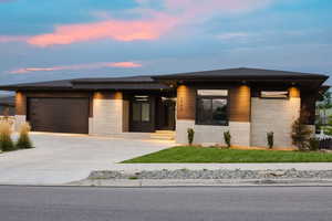 Prairie-style house featuring concrete block siding, driveway, a garage, and a front yard
