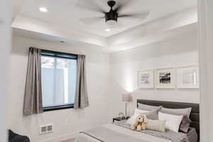 Bedroom featuring a raised ceiling, recessed lighting, and a ceiling fan