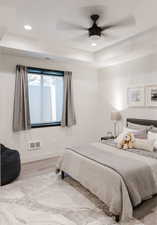 Bedroom with wood finished floors, a raised ceiling, recessed lighting, and ceiling fan