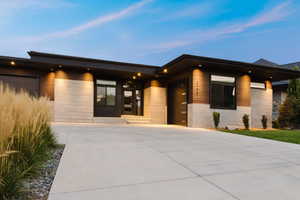 View of exterior entry with an attached garage, concrete block siding, and stone siding