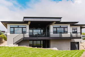Rear view of house with a lawn, stucco siding, a patio, and a garage