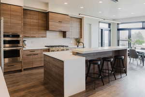 Kitchen featuring decorative light fixtures, recessed lighting, a kitchen breakfast bar, dark wood-style flooring, and a kitchen island with sink
