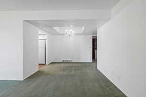 Unfurnished room with carpet, a chandelier, and a textured ceiling