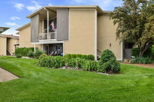 View of property exterior featuring a yard, stucco siding, and a balcony