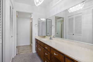Bathroom with a closet, vanity, a chandelier, and a stall shower