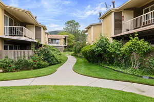 View of property's community featuring a lawn, a balcony, and a mountain view