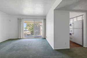 Unfurnished room with dark colored carpet and a textured ceiling