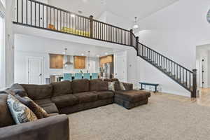 Living room featuring a high ceiling, stairs, recessed lighting, and light wood-type flooring