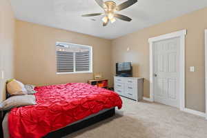 Bedroom featuring light carpet, a textured ceiling, and a ceiling fan