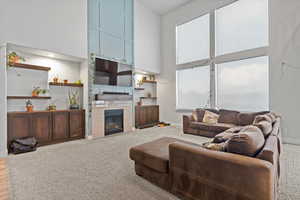 Living room featuring a towering ceiling, a large fireplace, and light carpet