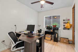 Office with light wood-type flooring and ceiling fan