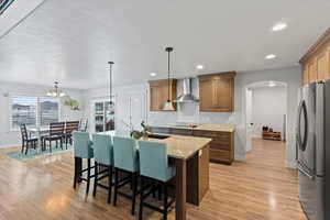 Kitchen featuring hanging light fixtures, freestanding refrigerator, a breakfast bar, light stone countertops, and arched walkways
