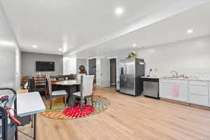 Kitchen featuring stainless steel appliances, light wood-style flooring, recessed lighting, open floor plan, and light stone countertops