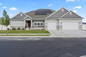 Craftsman inspired home featuring stone siding, stucco siding, a front yard, and roof mounted solar panels
