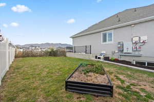 Fenced backyard featuring a mountain view, a garden, and a patio area