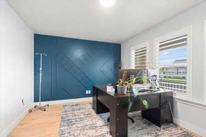 Office featuring light wood-style flooring and an accent wall