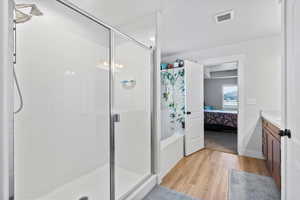Ensuite bathroom with a stall shower, light wood-type flooring, vanity, and a bath