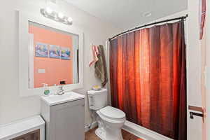 Full bath with vanity, a textured ceiling, wood finished floors, and a shower with shower curtain