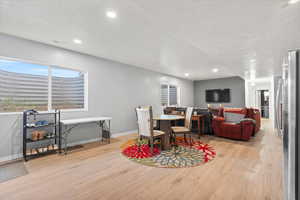 Dining room featuring light wood-style floors, a textured ceiling, and recessed lighting
