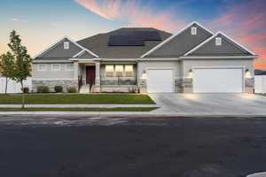 Craftsman-style home with stone siding, a lawn, concrete driveway, and stucco siding