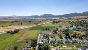 Aerial view of property and surrounding area featuring rural landscape, a water and mountain view, and nearby suburban area