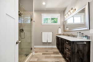 Full bathroom with vanity, a shower stall, and light wood-style flooring