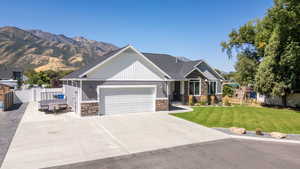 View of front of home featuring stone siding, driveway, a garage, and a mountain view