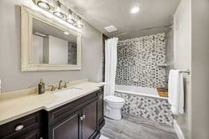 Full bathroom featuring tiled shower / bath, a textured ceiling, vanity, and recessed lighting